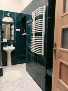 a green tiled bathroom with a sink and a mirror at Apartament Jaśminowy in Kudowa-Zdrój