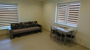 a room with a couch and a table and two windows at Aringos Rezidencija in Šventoji +5 photos