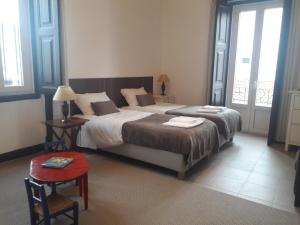 1 dormitorio con 1 cama grande y 2 ventanas en Casa do Beco do Beiçudo centro de Evora, en Évora