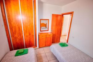 普拉亞戴爾雷安格萊斯的住宿－Apartamento al lado de la playa，一间卧室设有两张床和一个带绿色把手的梳妆台。