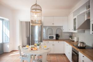 メッサリアにあるAleria Villa Santoriniの白いキャビネットとテーブル(食べ物付)が備わるキッチン