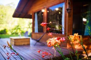 a wooden deck with flowers in front of a cabin at Cabanas Parque Suíço in São Francisco de Paula