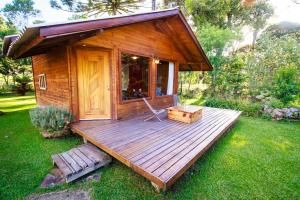 a small cabin with a deck in the grass at Cabanas Parque Suíço in São Francisco de Paula