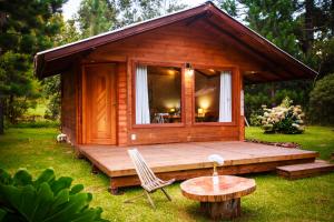 a small wooden cabin with a table and a chair at Cabanas Parque Suíço in São Francisco de Paula