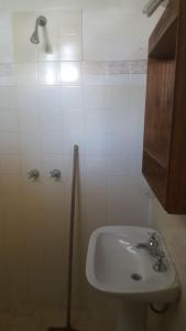 y baño blanco con lavabo y ducha. en Departamentos Calamuchita en Santa Rosa de Calamuchita