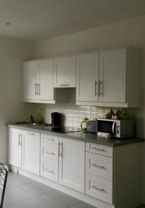 a kitchen with white cabinets and a microwave at Hazelbrook Killarney in Killarney