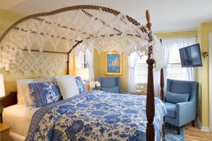 楠塔基特的住宿－七海街旅館，一间卧室配有天蓬床和2把蓝色椅子