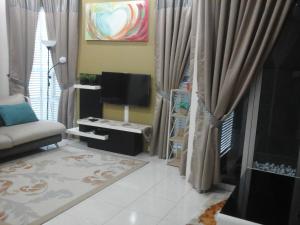 sala de estar con TV y sofá en Miker Homestay, en Seri Iskandar