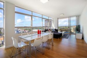 een eetkamer met een tafel, stoelen en ramen bij Gadigal Groove - Modern and Bright 3BR Executive Apartment in Zetland with Views in Sydney