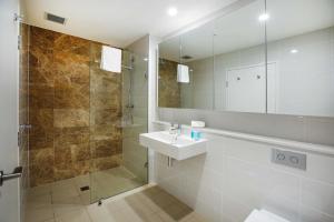 a bathroom with a sink and a shower with a mirror at Gadigal Groove - Modern and Bright 3BR Executive Apartment in Zetland with Views in Sydney