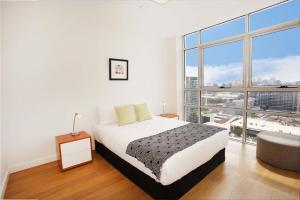 a white bedroom with a bed and a large window at Gadigal Groove - Modern and Bright 3BR Executive Apartment in Zetland with Views in Sydney