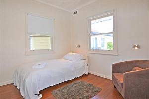 a bedroom with a bed and a chair and two windows at Breakers 4 2 Hill Street in Port Macquarie