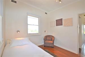 a white bedroom with a bed and a chair at Breakers 4 2 Hill Street in Port Macquarie