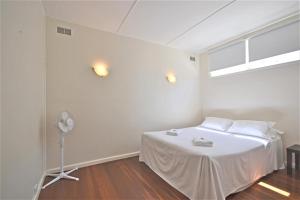 a white room with a bed and a fan at Breakers 5 2 Hill Street in Port Macquarie