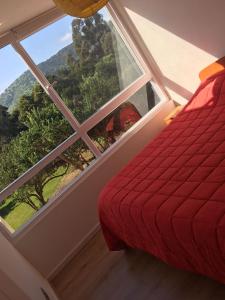 a bedroom with a red bed and a large window at Lomas 3 Bosque y Playa in Papudo