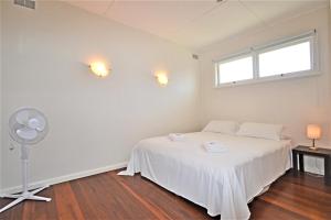 a bedroom with a white bed and a fan at Breakers 6 2 Hill Street in Port Macquarie