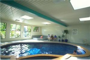 a large swimming pool in a building with people sitting around it at Best Western Plus The Tudor Box Hill in Box Hill