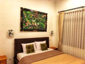 sypialnia z łóżkiem i obrazem na ścianie w obiekcie Agus Tri Homestay w mieście Sanur