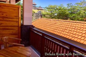 a balcony with a wooden table and a roof at Agus Tri Homestay in Sanur