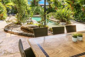 un patio con mesa, sillas y piscina en Cascade Gardens, en Cairns