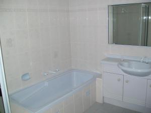 a white bathroom with a tub and a sink at Mainsail 10 17 Owen Street in Port Macquarie +7 photos