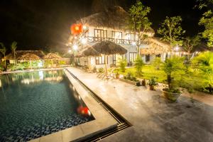 a villa with a swimming pool at night at Tam Coc Rice Fields Resort in Ninh Binh