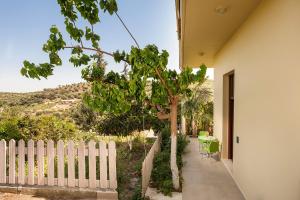 a white fence next to a house with a tree at Filio House in Stalos