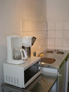 a kitchen with a coffee maker on top of a microwave at Appart Hotel de la Paix in Barcelonnette