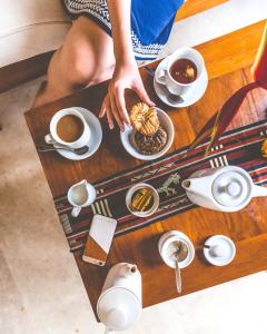 eine Person, die Essen auf einem Tisch mit Tassen Kaffee isst in der Unterkunft Munduk Moding Plantation Nature Resort in Munduk