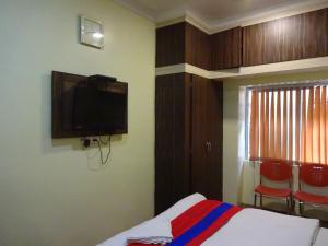 1 dormitorio con 1 cama y TV en la pared en Monovilla Inn en Calcuta