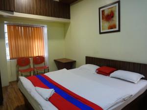 1 dormitorio con 1 cama con manta roja y azul en Monovilla Inn, en Calcuta