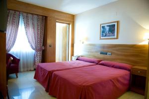 a bedroom with a large red bed with a window at Hotel La Maruxiña in La Alameda de la Sagra