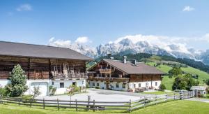 ein Haus mit einem Zaun und Bergen im Hintergrund in der Unterkunft Christernhof in Maria Alm am Steinernen Meer