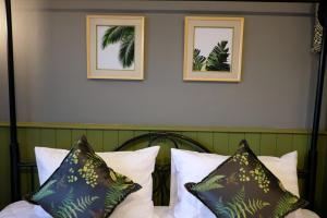 ein Bett mit Kissen und zwei gerahmte Bilder an der Wand in der Unterkunft TANA CASA 12 Large Sathorn 6BR Townhome with Parking in Bangkok + 5 Fotos