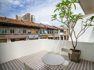 una mesa y una silla en un balcón con un árbol en Hutton Central Hotel By PHC en George Town