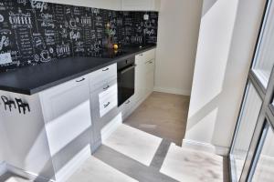 a kitchen with white cabinets and a black counter top at Loft on Owl Hill in Kaunas