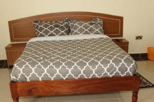 a bed with a wooden headboard and two pillows at Gees Inn in Nakuru