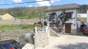 een klein huis met een stenen muur en een bord bij Casa Rural Fuentesil in Robles de Laciana