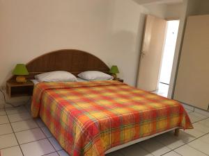 a bedroom with a bed with a orange and yellow blanket at Residence Le Royaume du Soleil in Sainte-Anne