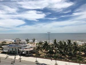 a view of a beach with a building and palm trees at Khách sạn Hồ Gươm in Sầm Sơn +20 photos