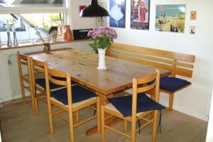 een houten tafel met stoelen en een vaas met bloemen bij Woody B&B in Jelling