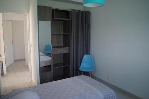a bedroom with a bed and a blue chair at Ti Korelo Guidel in Guidel