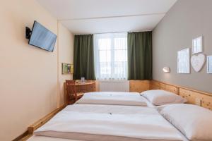 a bedroom with two beds and a desk and a television at JUFA Hotel Bad Aussee in Bad Aussee