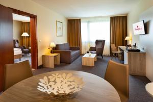 um quarto de hotel com uma mesa e uma sala de estar em Hotel Ramada Graz em Premstätten