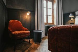 a bedroom with a chair and a bed and a window at Langley Hotel Gustavia in Chamonix