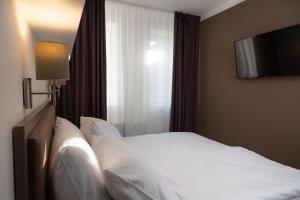 a white bed sitting in a bedroom next to a window at Skyhotel Prague in Prague
