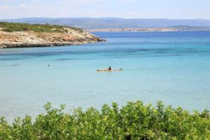 a person in a yellow boat in the water at Hotel Punta Negra in Alghero