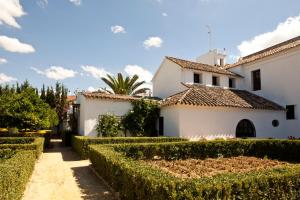 a white house with hedges in front of it at Monasterio de San Francisco in Palma del Río