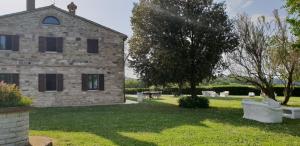 un antico edificio in pietra con sedie e un albero di Villa delle Fonti di Portonovo ad Ancona