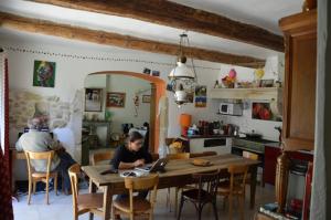 Les Granges-Gontardes的住宿－Chez Germaine，两人坐在厨房的桌子上,厨房配有笔记本电脑